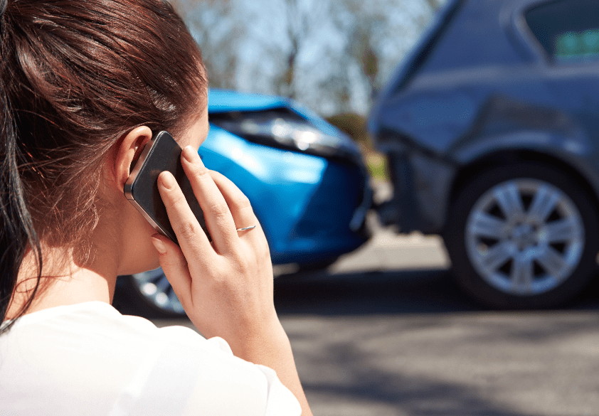 una mujer conductor hace una llamada telefonica despues de un accidente de trafico mirando el accidente min